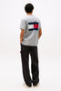Person wearing a Tommy Jeans t-shirt with a flag logo on the back, standing against a white background.