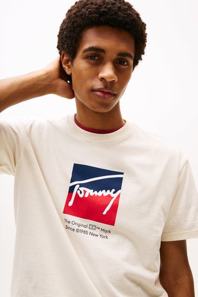Person wearing a white t-shirt with a Tommy Hilfiger logo on a white background