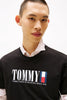 Person wearing a black Tommy Jeans t-shirt with a white background
