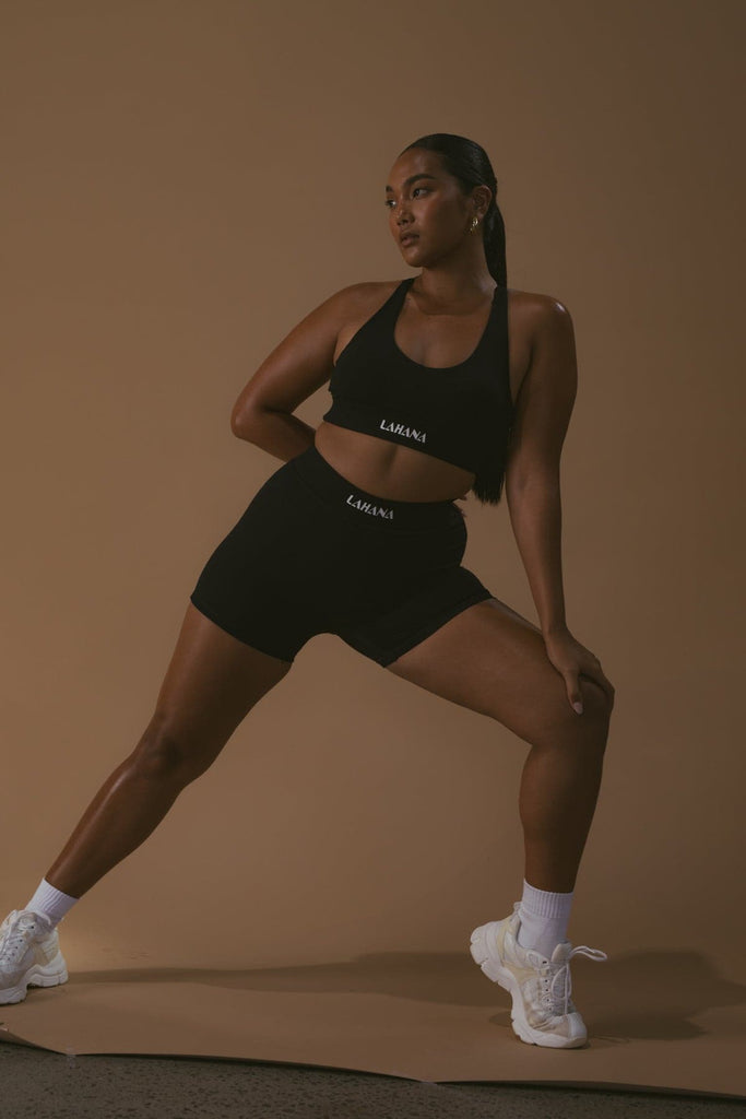 A model stretching while wearing the Lahana Active Sanaa Crop Top in Black.